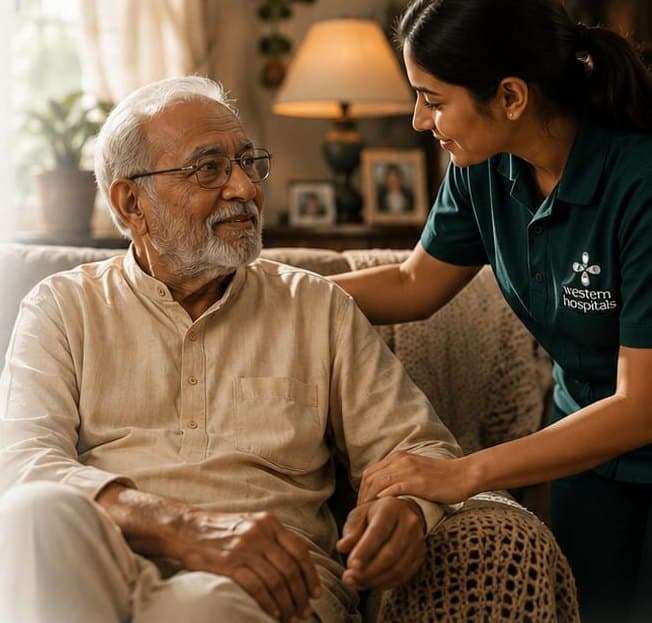 A Western Hospitals care monitor sits with an elderly man in his living room, a reassuring hand on his shoulder.